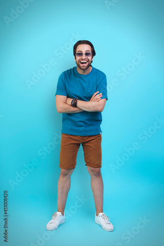 Excited young man in casual clothing gesturing and smiling while standing against yellow background