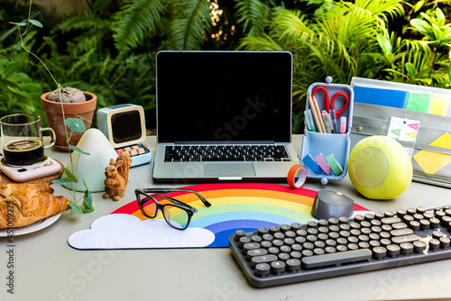 The garden workbench has computers, pens, pencils, keyboards, coffee and croissants on the table.