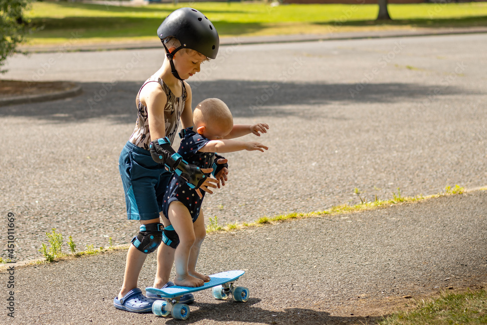 Obraz premium older brother teaches baby to skate