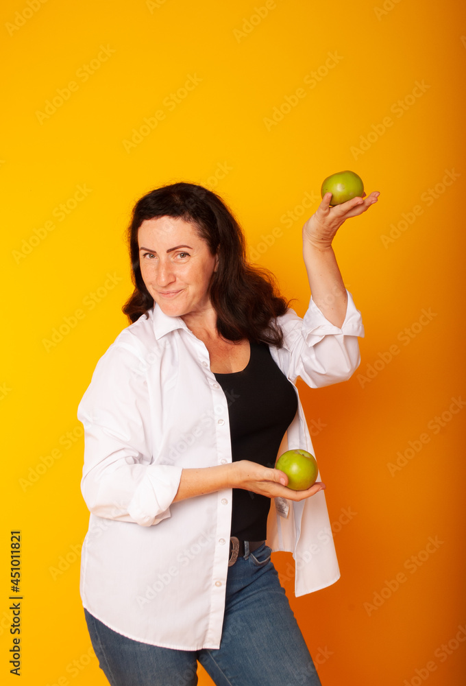 woman on a yellow background with apples in her hands, slimming. healthy lifestyle. Vegan day. woman on a yellow background with apples in her hands, slimming. healthy lifestyle. Vegan day.