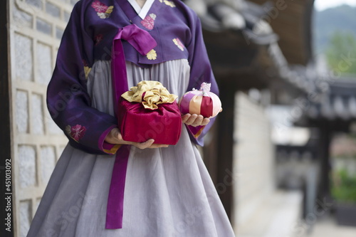 Woman in Korean traditional clothes holding traditional package with lucky bag