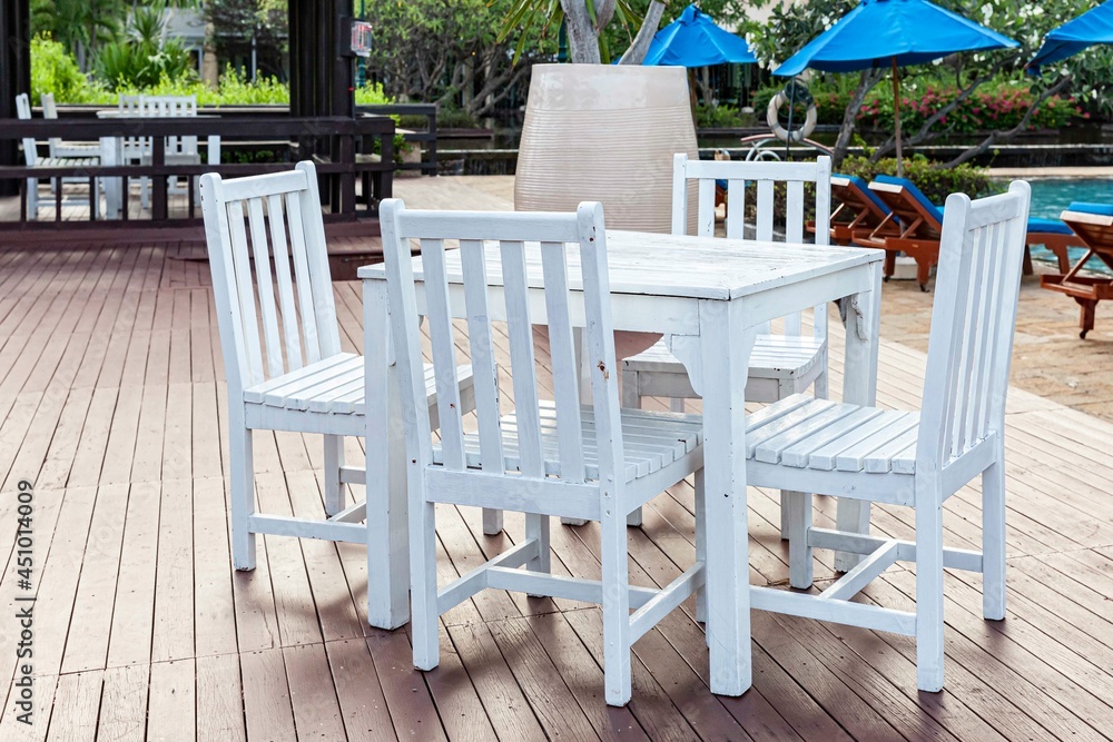 White wooden dining table by the pool inside the resort