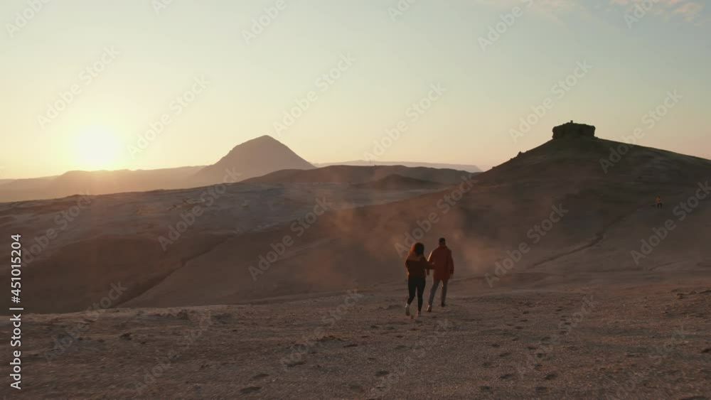Aerial Shot of a Couple Running Towards a Mountain, and Sunset in Background Aerial Shot of a Couple Running Towards a Mountain, and Sunset in Background
