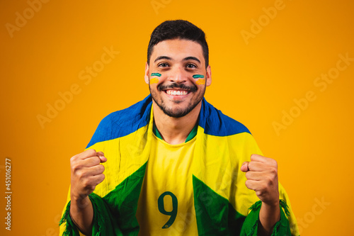 brazilian fan cheering in the crowd on yellow background. photo