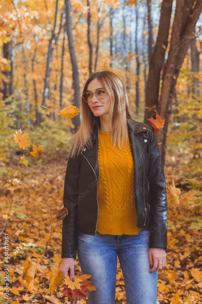 Cute smiley woman holding autumn leaves in fall park. Seasonal, lifestyle and leisure concept. Cute smiley woman holding autumn leaves in fall park. Seasonal, lifestyle and leisure concept.