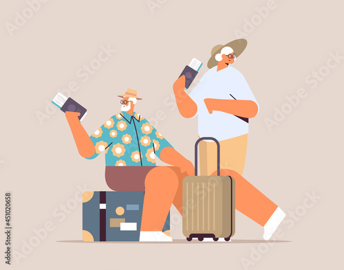 elderly couple of tourists grandparents with luggage holding passports and tickets ready to boarding at airport