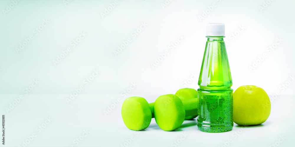 Green apple, bottle with natural juice and dumbbells. Banner with place for text. Green apple, bottle with natural juice and dumbbells. Banner with place for text.
