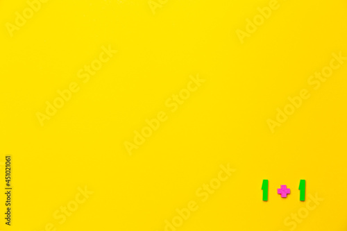 One plus 1 equals two is example on yellow background. Copy space. Math lesson. Primary count teaching. Online course of distance education design mockup. Flat lay. Text place. Back to school