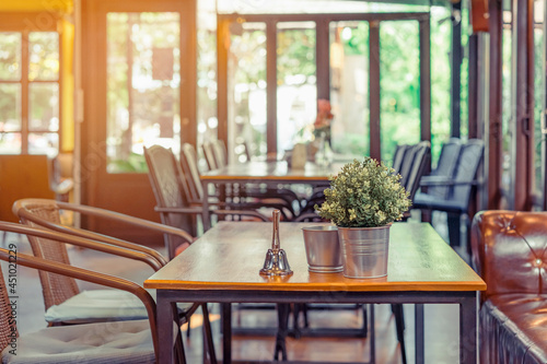 A small bell for calling the waiter and artificial flowers in an aluminum pot placed on a table in a coffee shop.