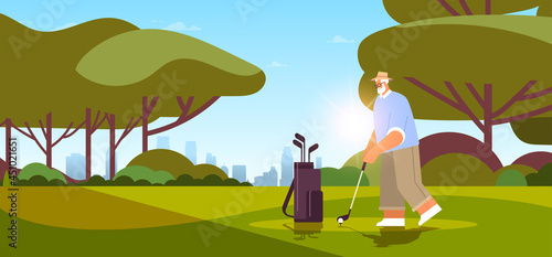 senior man playing golf on green golf course aged player taking a shot active old age concept landscape background