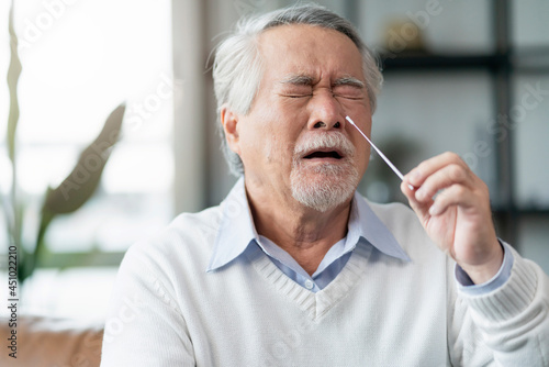 Old senior asian male hand nasal swab testing rapid tests by himself for detection of the SARS co-2 virus at home isolate quarantine concept