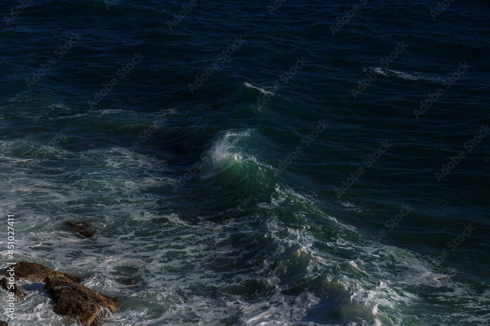 Ocean wave background breaking sea water rocky shore rough seas turquoise water gradient foam. Big waves at open sea. Summer monsoon. White crest of a sea wave. Ocean wave background breaking sea water rocky shore rough seas turquoise water gradient foam. Big waves at open sea. Summer monsoon. White crest of a sea wave.