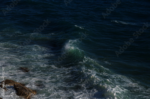 Ocean wave background breaking sea water rocky shore rough seas turquoise water gradient foam. Big waves at open sea. Summer monsoon. White crest of a sea wave.