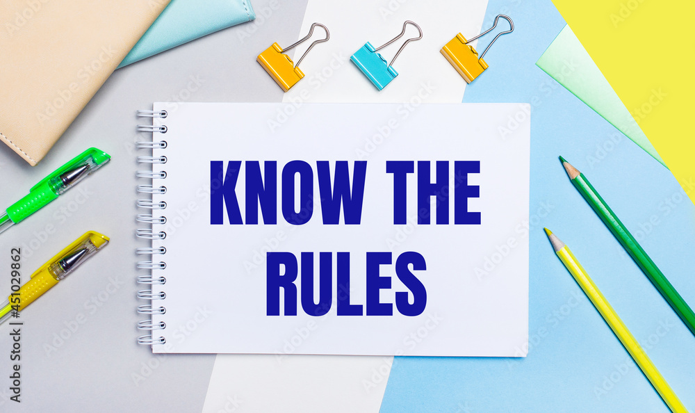 On a gray and blue background are stationery of yellow-green color, a notebook with the text KNOW THE RULES. Flat lay. On a gray and blue background are stationery of yellow-green color, a notebook with the text KNOW THE RULES. Flat lay.
