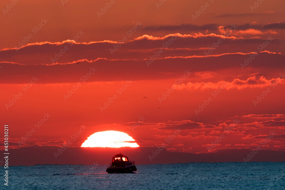 A small boat sets out to sea in the sunrise A small boat sets out to sea in the sunrise