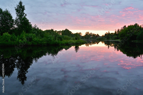 Fototapeta Naklejka Na Ścianę i Meble -  Sunrise over river with colorful clouds in sky, reflected in calm water. A picturesque early morning. Concept of nature, summer, travel and seasons