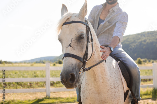 The handsome man rides a horse on a ranch