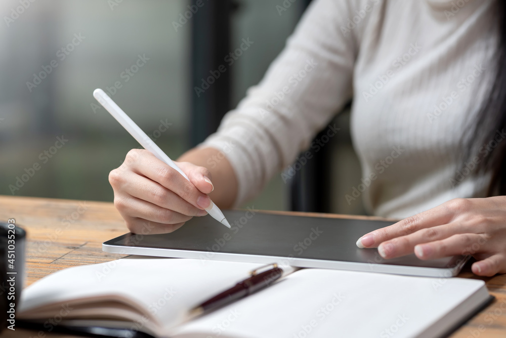Close-up of a woman hand holding a stylus with a tablet at the office Close-up of a woman hand holding a stylus with a tablet at the office