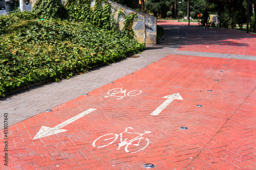 Red bicycle lane with two-way arrows in a park photo