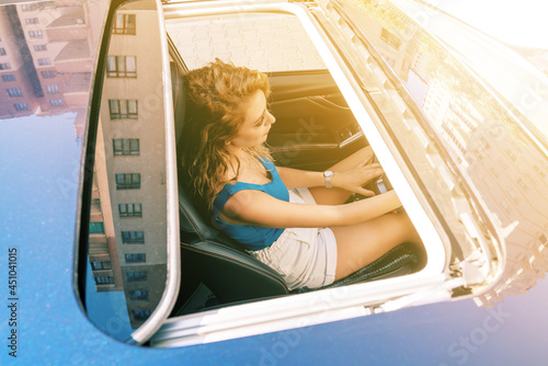 Top view from sunroof of a young beautiful woman sitting on car seat and drive carefuly.  photo