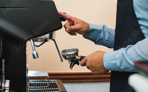 Selective focus and close up on barista s hands preparing coffee for customers and using equipment  pressing machine for brewing in indoor cafe shop. Business and Beverage Concept.