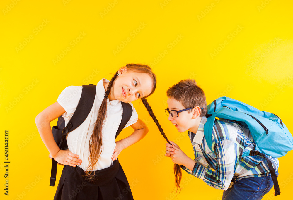 Obraz premium The cute little schoolboy pulls the schoolgirl's braid