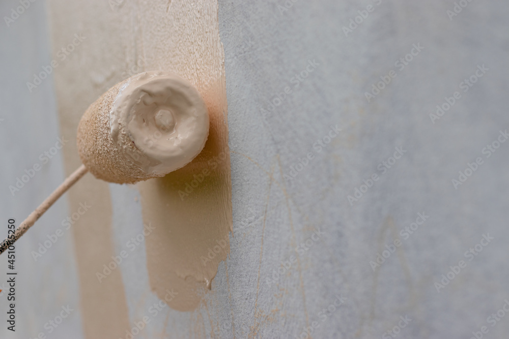 Obraz na plátně A painter's hand is painting old dilapidated walls with a paint roller