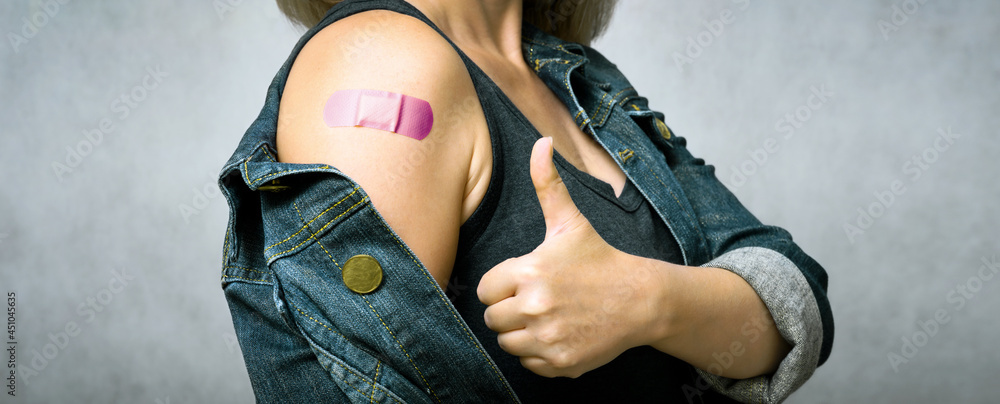 Woman showing shoulder with plaster after getting COVID-19 vaccine - obrazy, fototapety, plakaty 