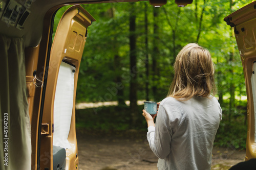 Wallpaper Mural Young blonde woman in pijama enjoys a morning coffee or tea outside her camper van in Frankenjura forest. Relax surrounded by nature, waking up in the car. Torontodigital.ca