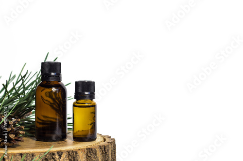 Two glass jars with yellow oil and pine plant extract on a tree cut. White background. Place for inscriptions and text.