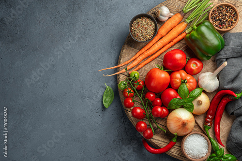 A set of fresh vegetables and spices for cooking a vegetable dish on a gray-blue background.
