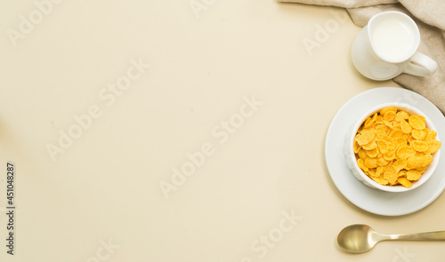 Popular instant breakfast: Cornflakes and a jug of milk on the table. View from above