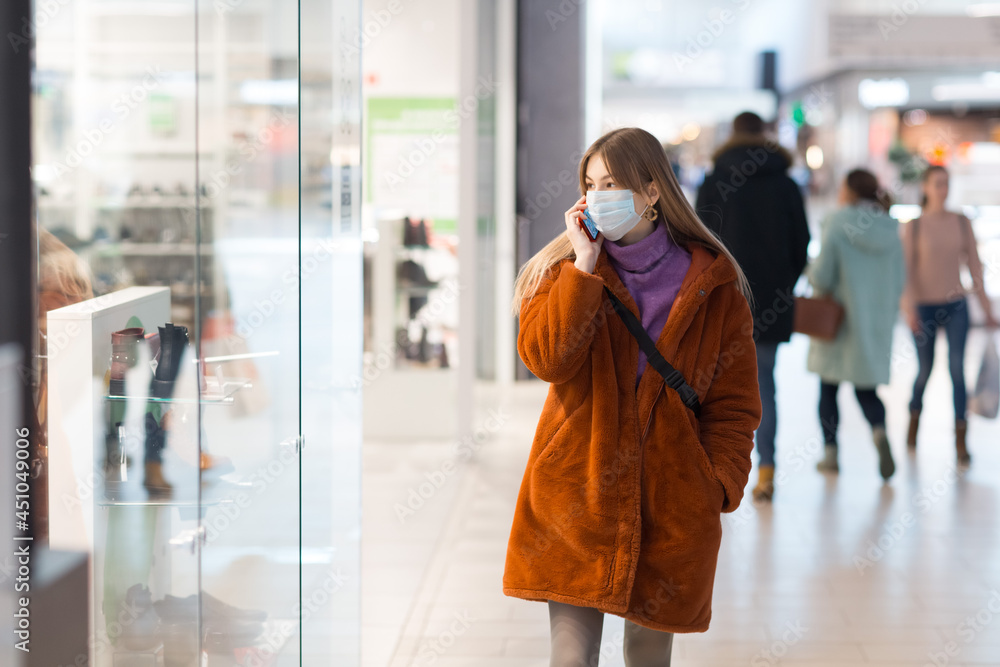 Young asian woman in medical mask with a phone at shop market. Young asian woman in medical mask with a phone at shop market.