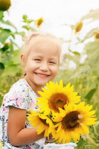 funny little girl in the field with sunflower flowers, summer time