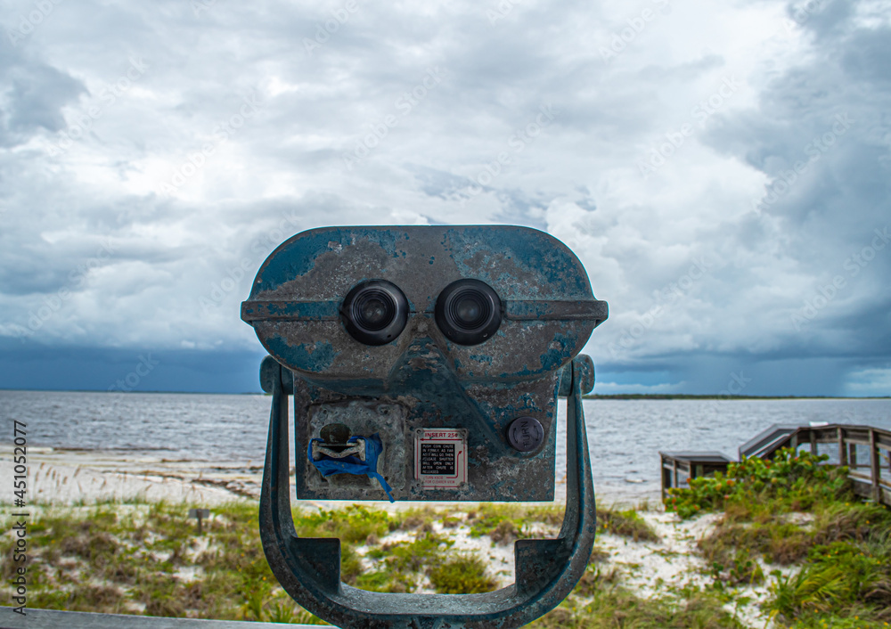 Binoculars view the storm. Port Boca Grande Lighthouse and Museum stand strong on Gasparilla Island as a tropical storm with black clouds loom of the coast in the Gulf of Mexico