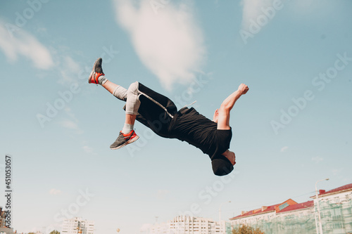 Young sporty guy doing parkour at the city street photo