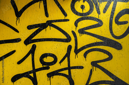 Abstract fragment of creative black scribble on yellow painted concrete wall. Modern background