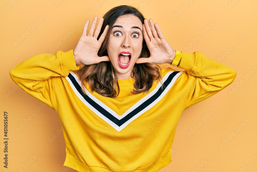Young hispanic girl wearing casual clothes smiling cheerful playing peek a boo with hands showing face. surprised and exited Young hispanic girl wearing casual clothes smiling cheerful playing peek a boo with hands showing face. surprised and exited