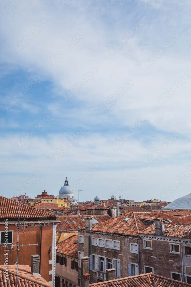 Dome of Basilica of Santa Maria della Salute over  traditional Venetian houses under blue sky in Venice, Italy