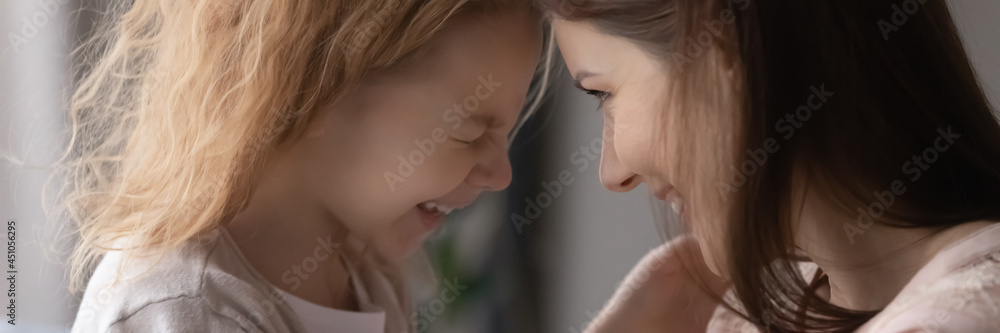 Close up narrow web panoramic view of overjoyed small girl child and young mother have fun together. Banner of smiling little teen daughter and mom play hug and cuddle. Unity, motherhood concept. Close up narrow web panoramic view of overjoyed small girl child and young mother have fun together. Banner of smiling little teen daughter and mom play hug and cuddle. Unity, motherhood concept.