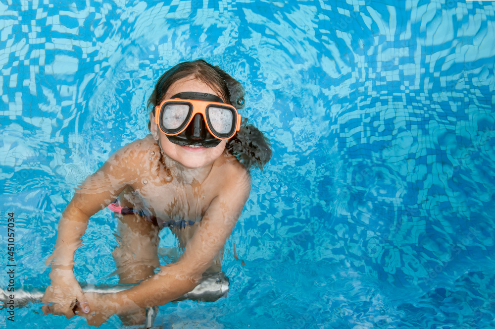 Naklejka premium Portrait of a smiling girl with goggles in a swimming pool. Vacation concept, aquatic, pool and water