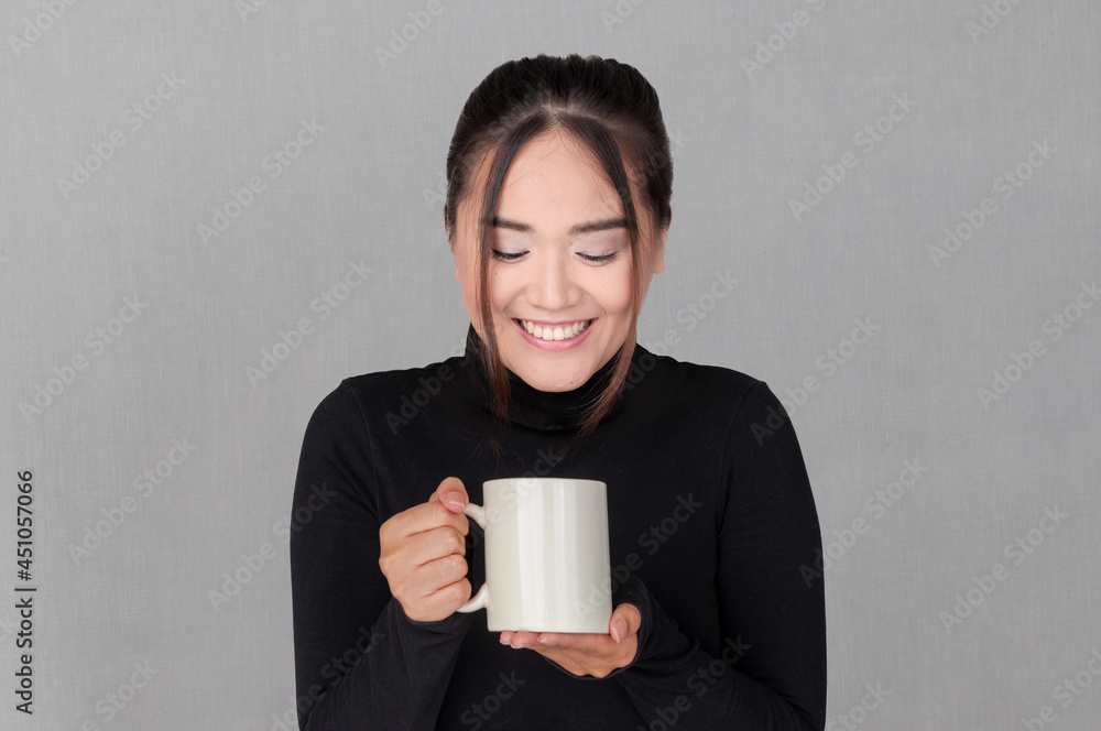 Woman of Chinese origin smiles as she looks at her cup of coffee. Young girl in black shirt Woman of Chinese origin smiles as she looks at her cup of coffee. Young girl in black shirt