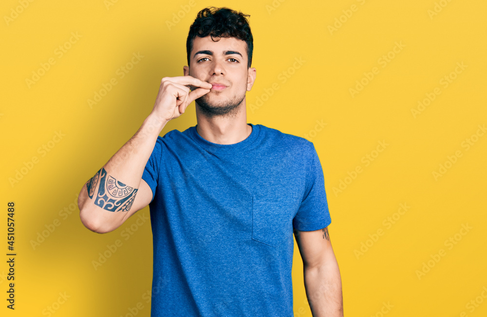 Young hispanic man wearing casual t shirt mouth and lips shut as zip with fingers. secret and silent, taboo talking Young hispanic man wearing casual t shirt mouth and lips shut as zip with fingers. secret and silent, taboo talking