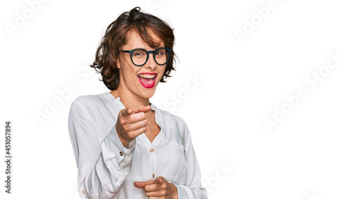 Young hispanic woman wearing business style and glasses pointing fingers to camera with happy and funny face. good energy and vibes.
