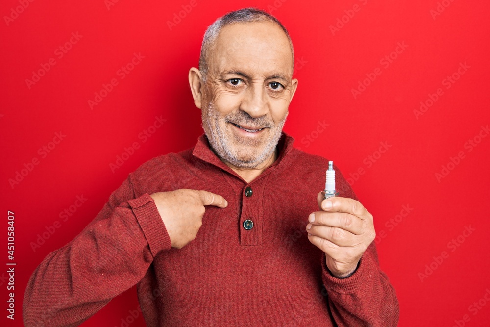 Handsome mature man holding spark plug pointing finger to one self smiling happy and proud Handsome mature man holding spark plug pointing finger to one self smiling happy and proud