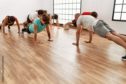 Group of young people training push-up pectoral exercise with personal trainer at sport center. © Krakenimages.com