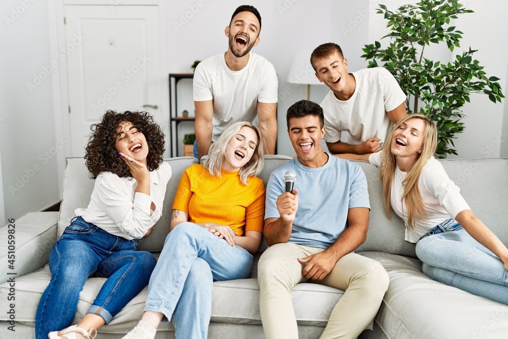 Group of young friends having party singing song using microphone at home. Group of young friends having party singing song using microphone at home.