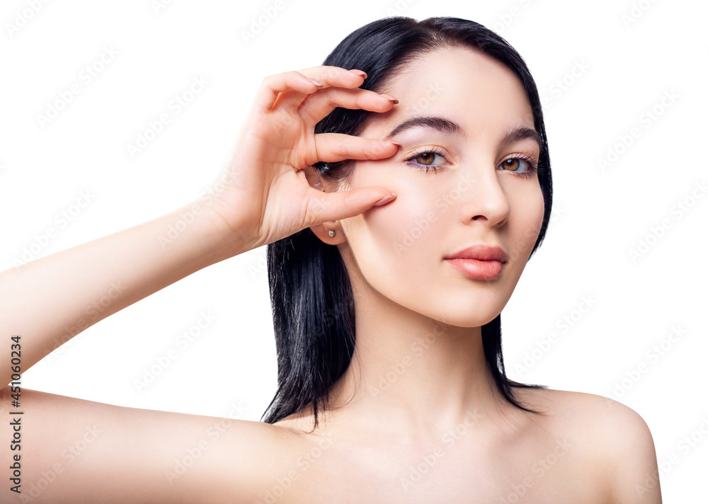 Young brunette woman with perfect skin shows area on face by hand.