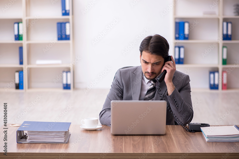 Young attractive male employee sitting at workplace Young attractive male employee sitting at workplace