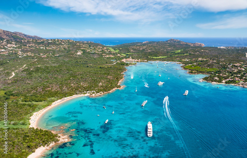 View from above, stunning aerial view of the Cala di volpe bay with a green coastline, white sand beaches and luxury yachts sailing on a turquoise water. Liscia Ruja, Costa Smeralda, Sardinia, Italy.